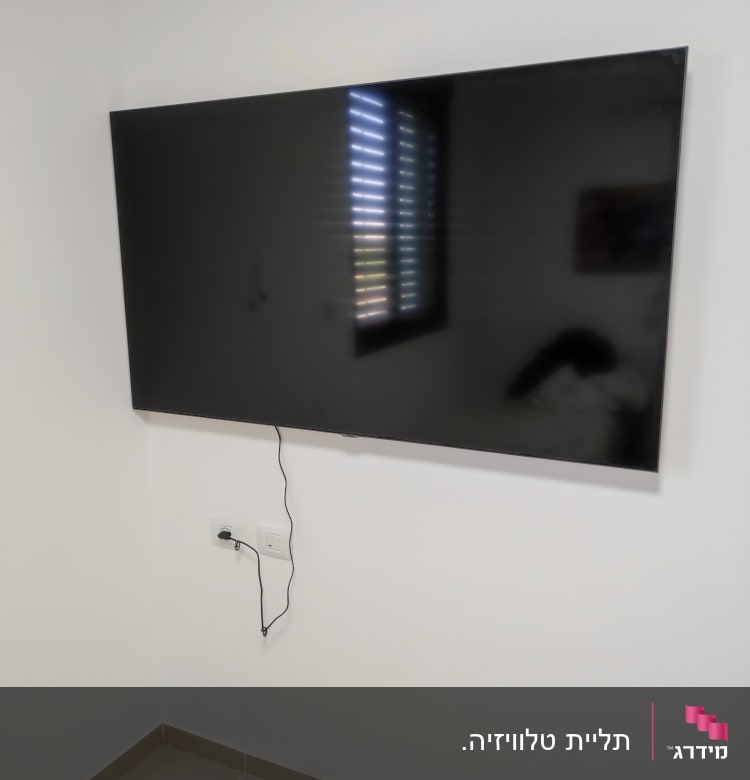 טלוויזיה תלויה על הקיר עם כבל חשמל מחובר